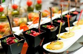 Présentation soignée de bouchées apéritives et verrines colorées, servies dans des contenants noirs modernes avec des mini-cuillères métalliques.