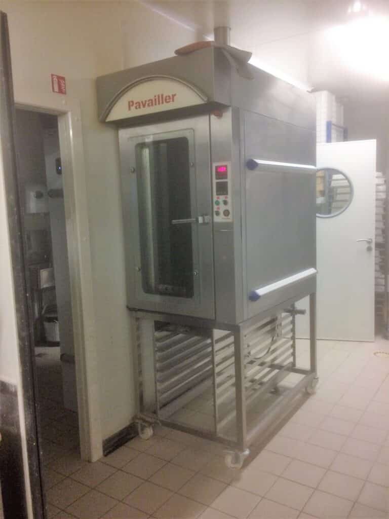 Four de boulangerie professionnel Pavailler en acier inoxydable avec affichage numérique 13:00, sur roulettes, dans une cuisine. Panneau extincteur visible.