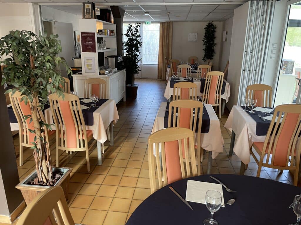 Salle de restaurant moderne avec tables dressées (nappe pêche, chemin de table marine), chaises bois orange, plantes vertes. Affiche 