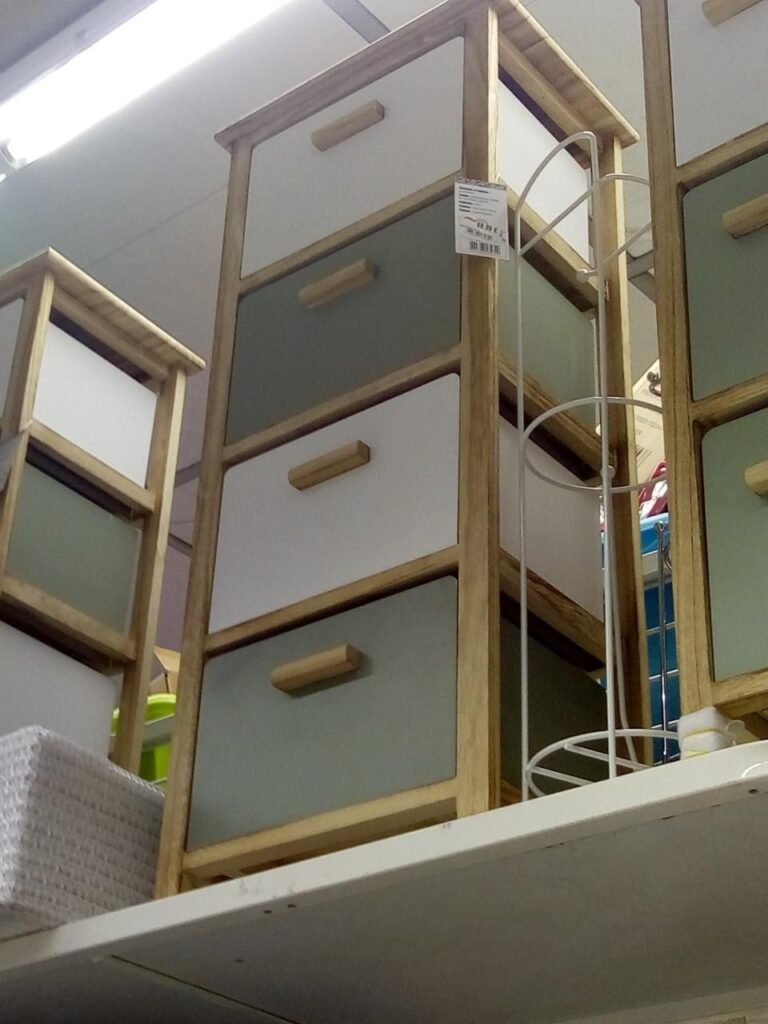 Meuble de rangement en bois clair à 4 tiroirs bicolores (blanc/vert sauge) avec poignées en bois. Prix: 18,99 €.