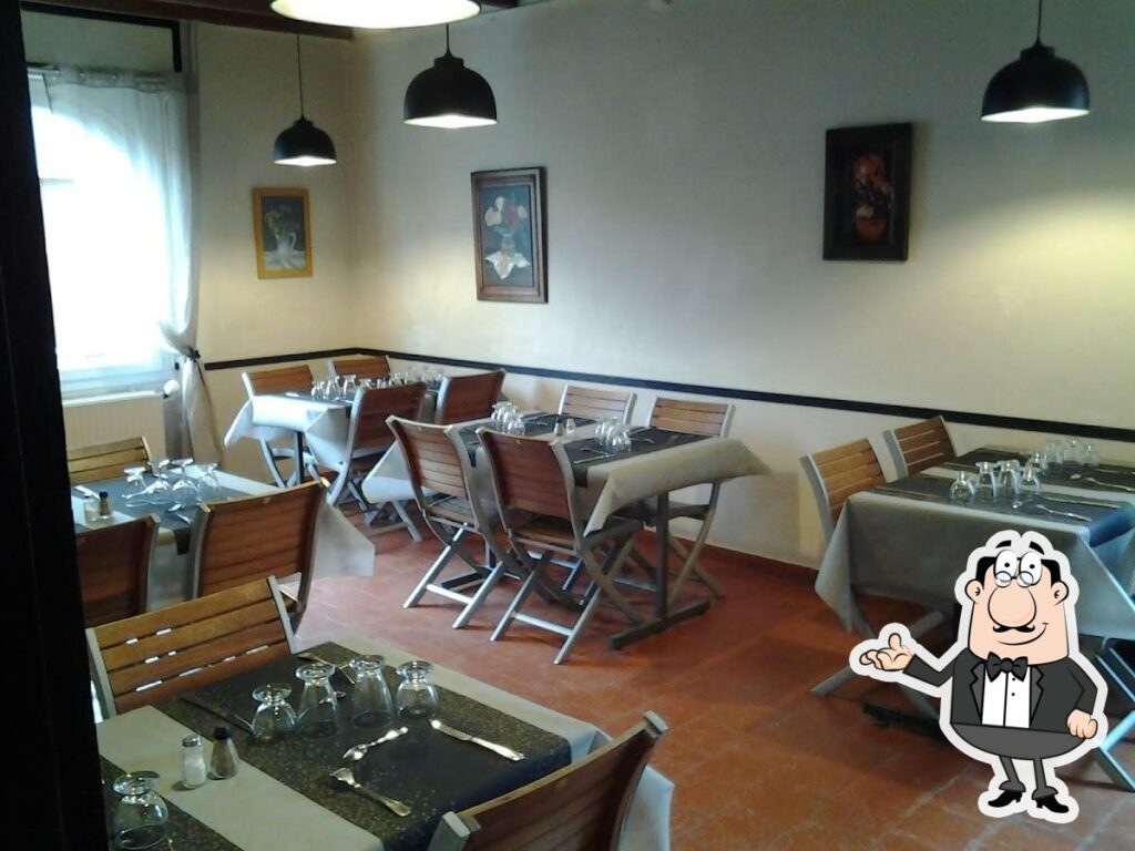 Intérieur de restaurant chaleureux avec tables dressées, chaises en bois, tableaux muraux et lumières suspendues. Grande fenêtre.