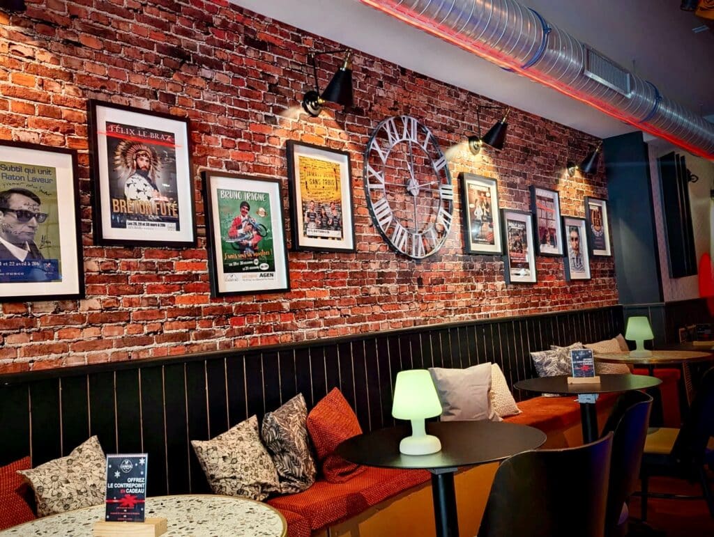 Intérieur de café-théâtre cosy: mur de briques, affiches 