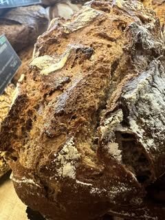 Gros plan sur une miche de pain artisanal rustique, croûte craquelée et farinée, apparence riche et dorée.