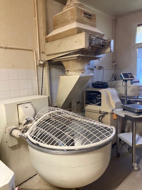 Pétrin de boulangerie industriel blanc avec grille de sécurité et doseur de farine Estève en arrière-plan.