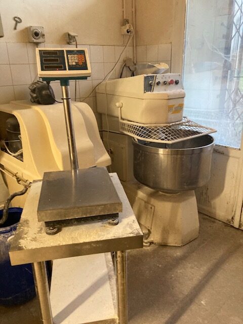 Pétrin à spirale et balance électronique couverts de farine dans un laboratoire de boulangerie.