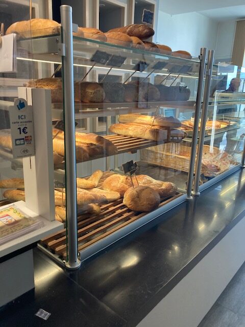 Vitrine de boulangerie avec baguettes et miches de pain frais, panneau carte acceptée à partir de 1€.