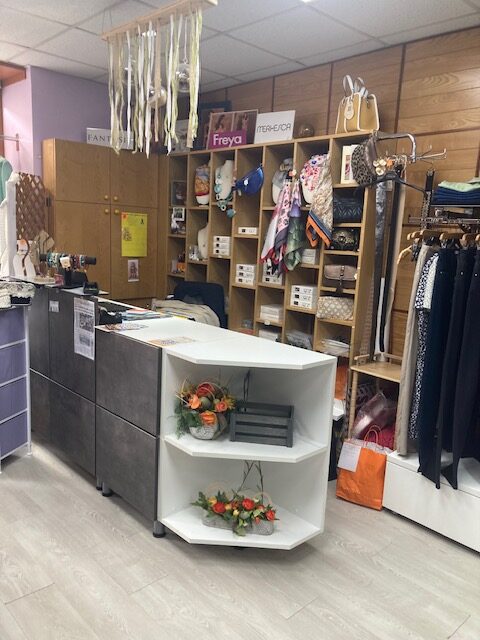 Intérieur d'une boutique de mode avec comptoir moderne, sacs, foulards et marques Freya et MERKESCA.