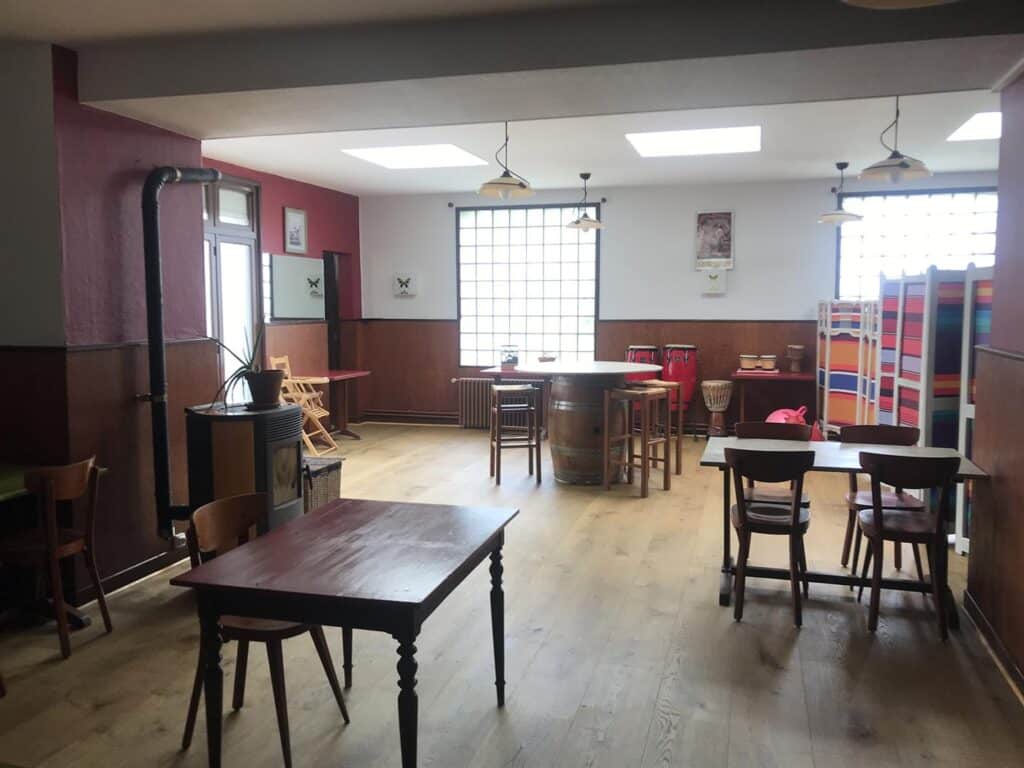 Intérieur de café rustique avec mobilier en bois, poêle à bois et baril de vin entouré d'instruments de musique.