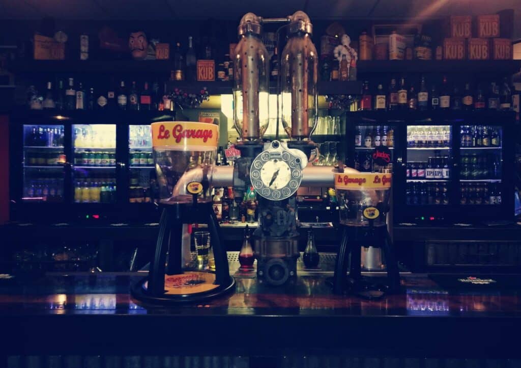 Tireuses à bière Le Garage et pompe à essence vintage sur un comptoir de bar rétro avec bouteilles de Kub.