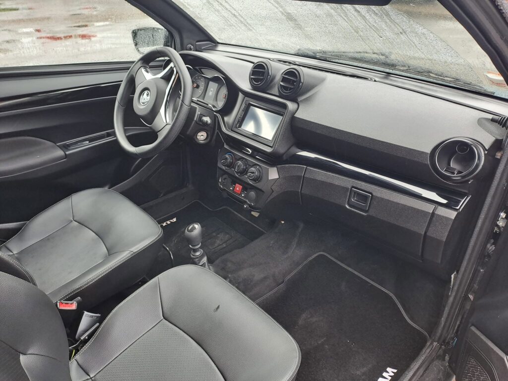Intérieur Aixam noir avec écran tactile et sièges en similicuir.