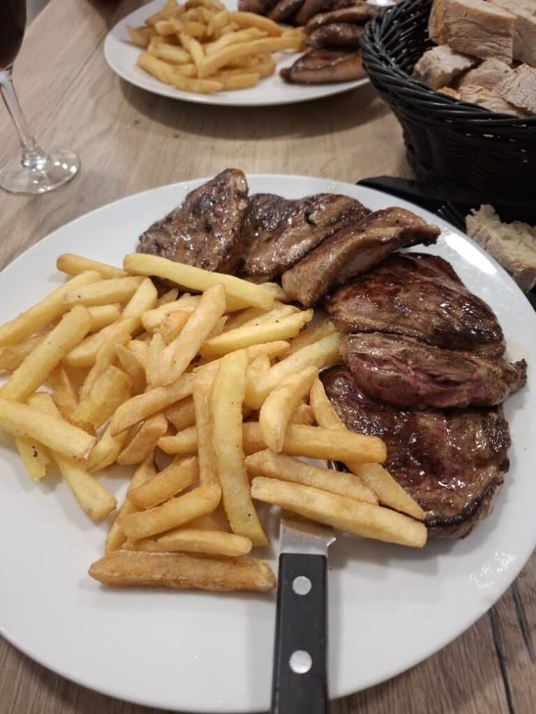 Magret de canard grillé et frites croustillantes sur assiette blanche au restaurant.
